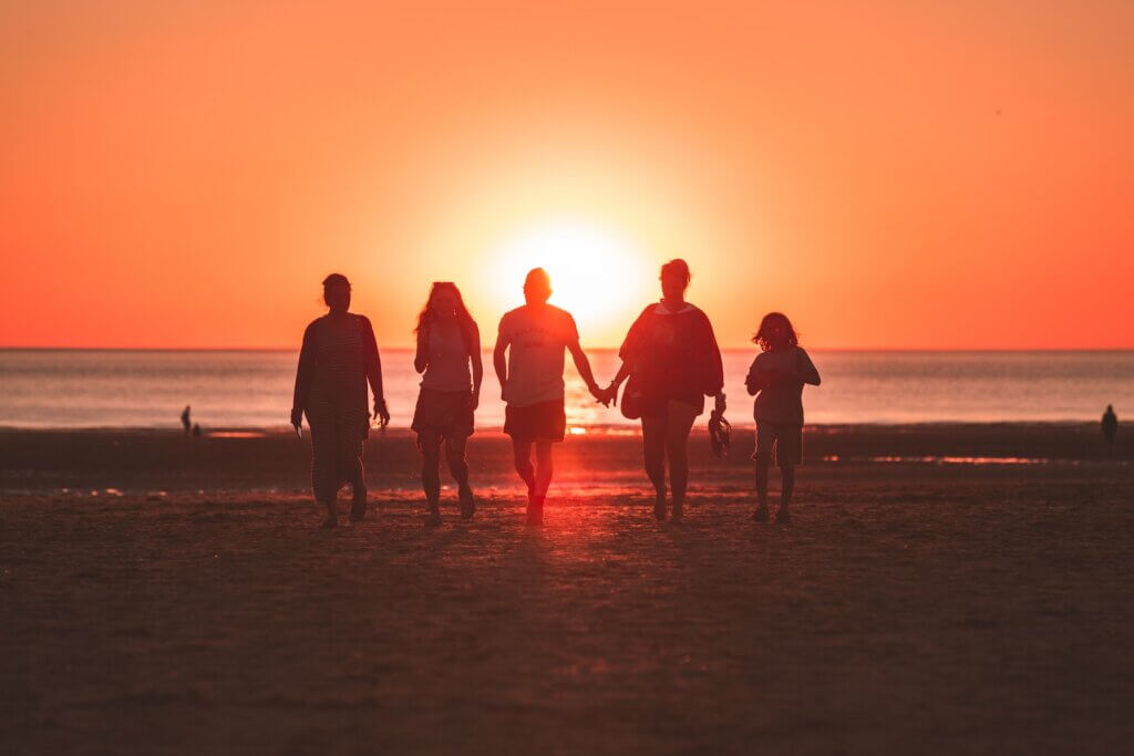 Family of five walking towards the camera at the beach during golden hour - photo