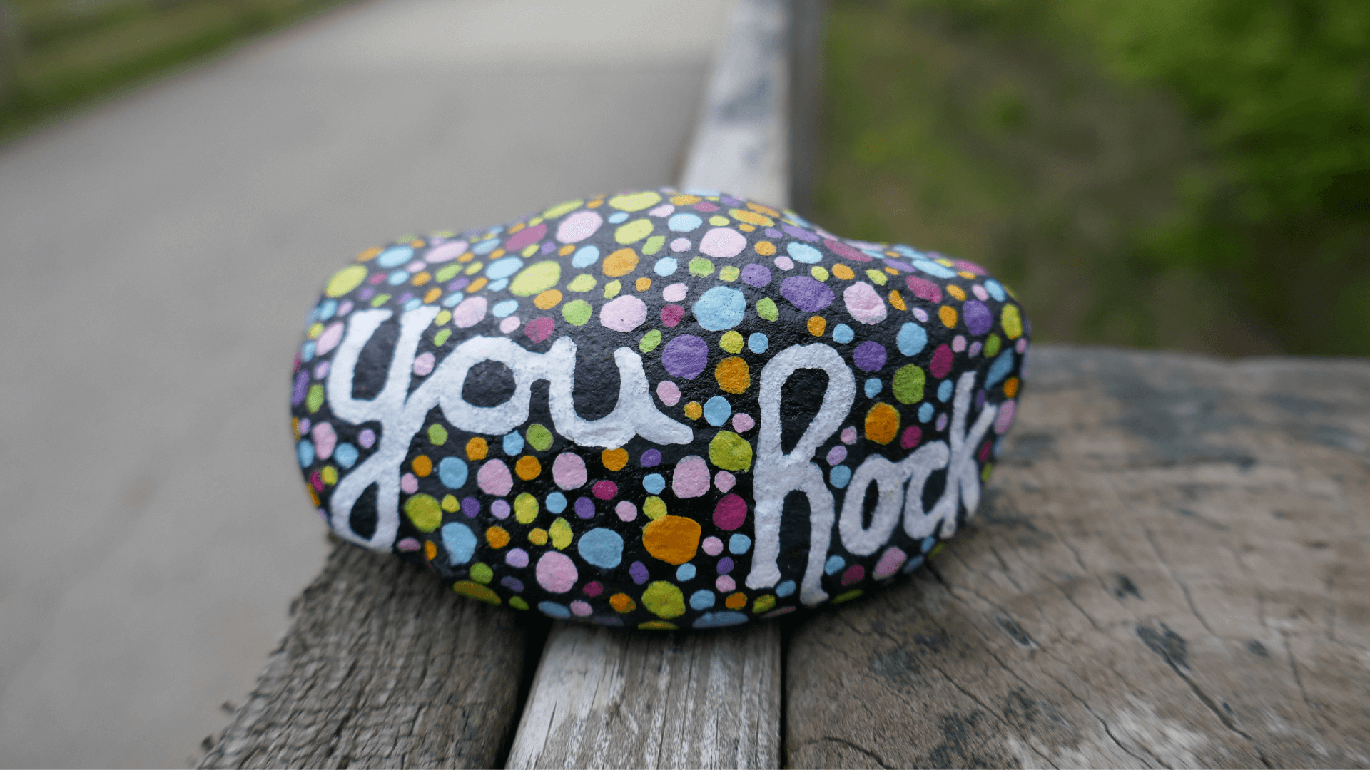 words "You Rock" and colorful dots painted on a small rock