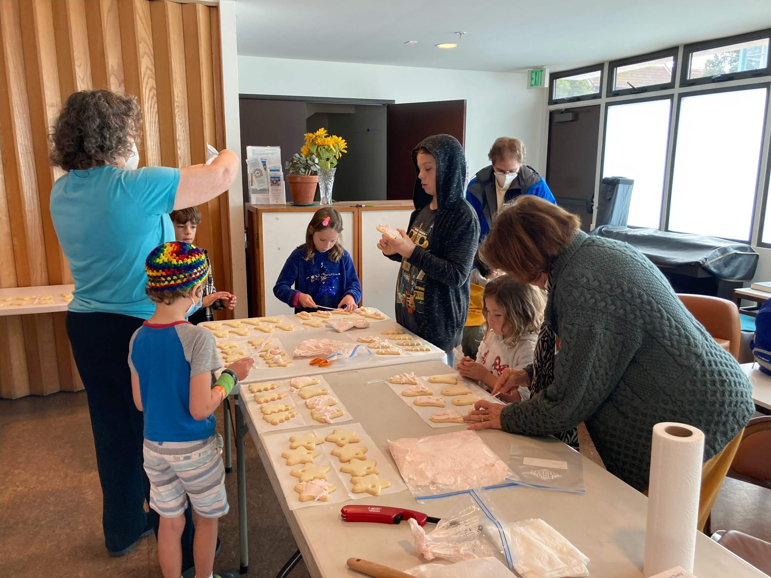 Kids and adults frosting dozens of cookies for food insecure persons served by Grass Roots Neighbors