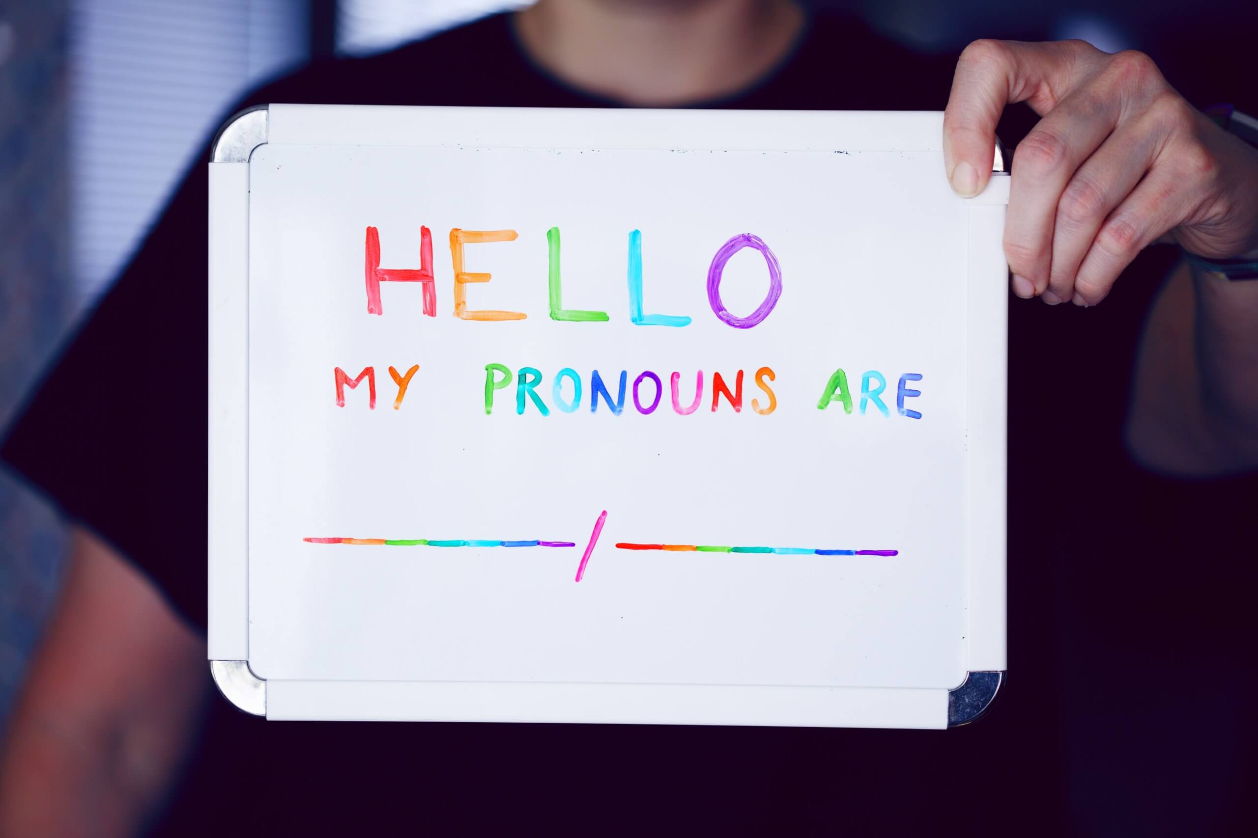 Whiteboard inscribed with text inviting persons to declare pronouns