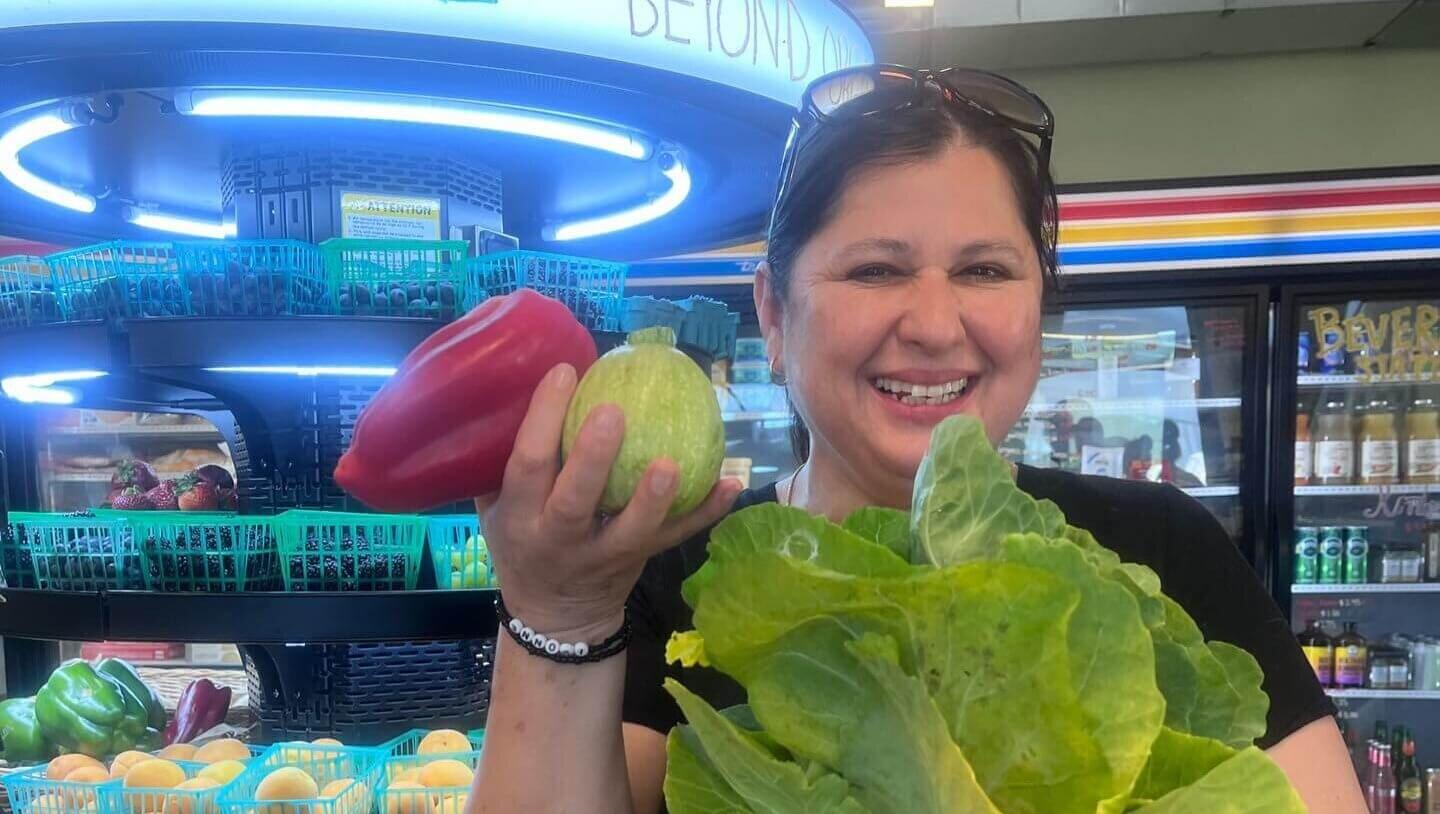 Woman in market holds up fresh produce