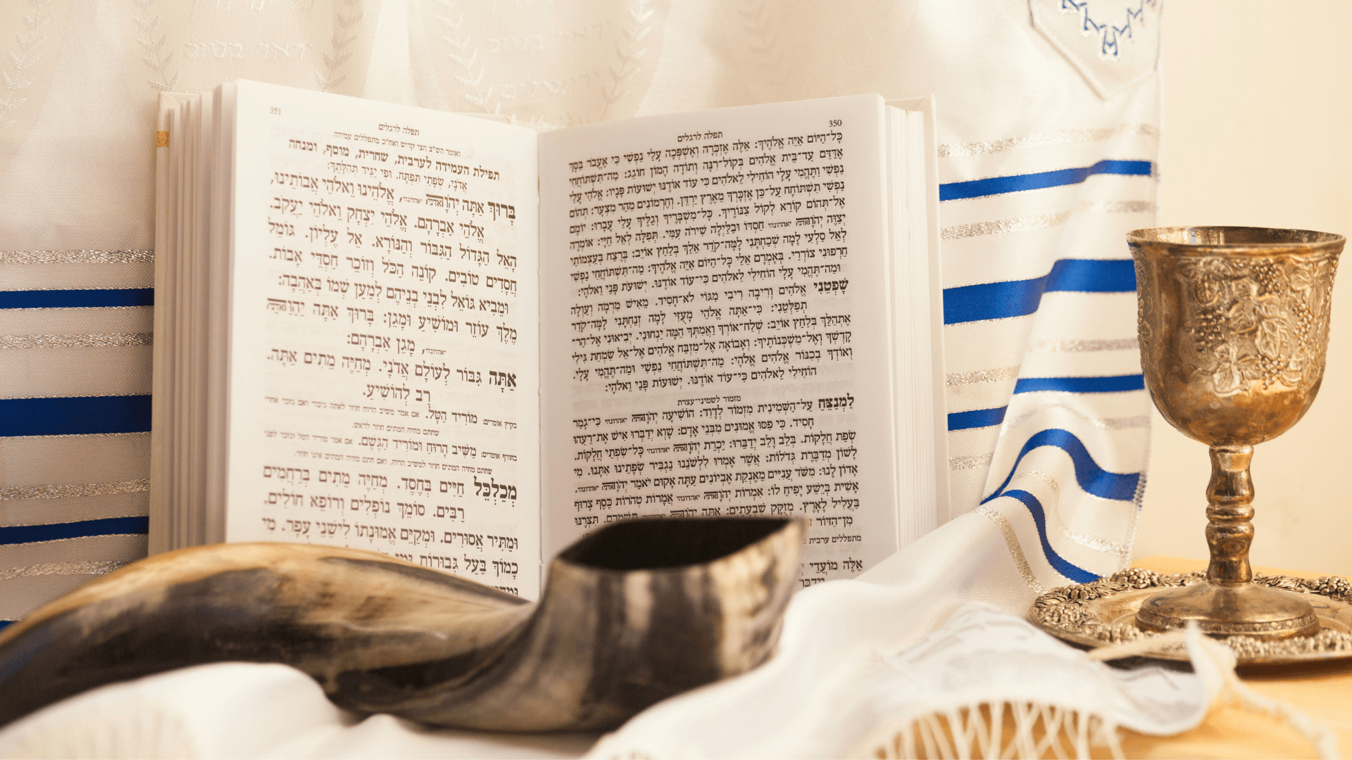 book in Hebrew, Shofar (horn), tall brass cup, white and blue shawl