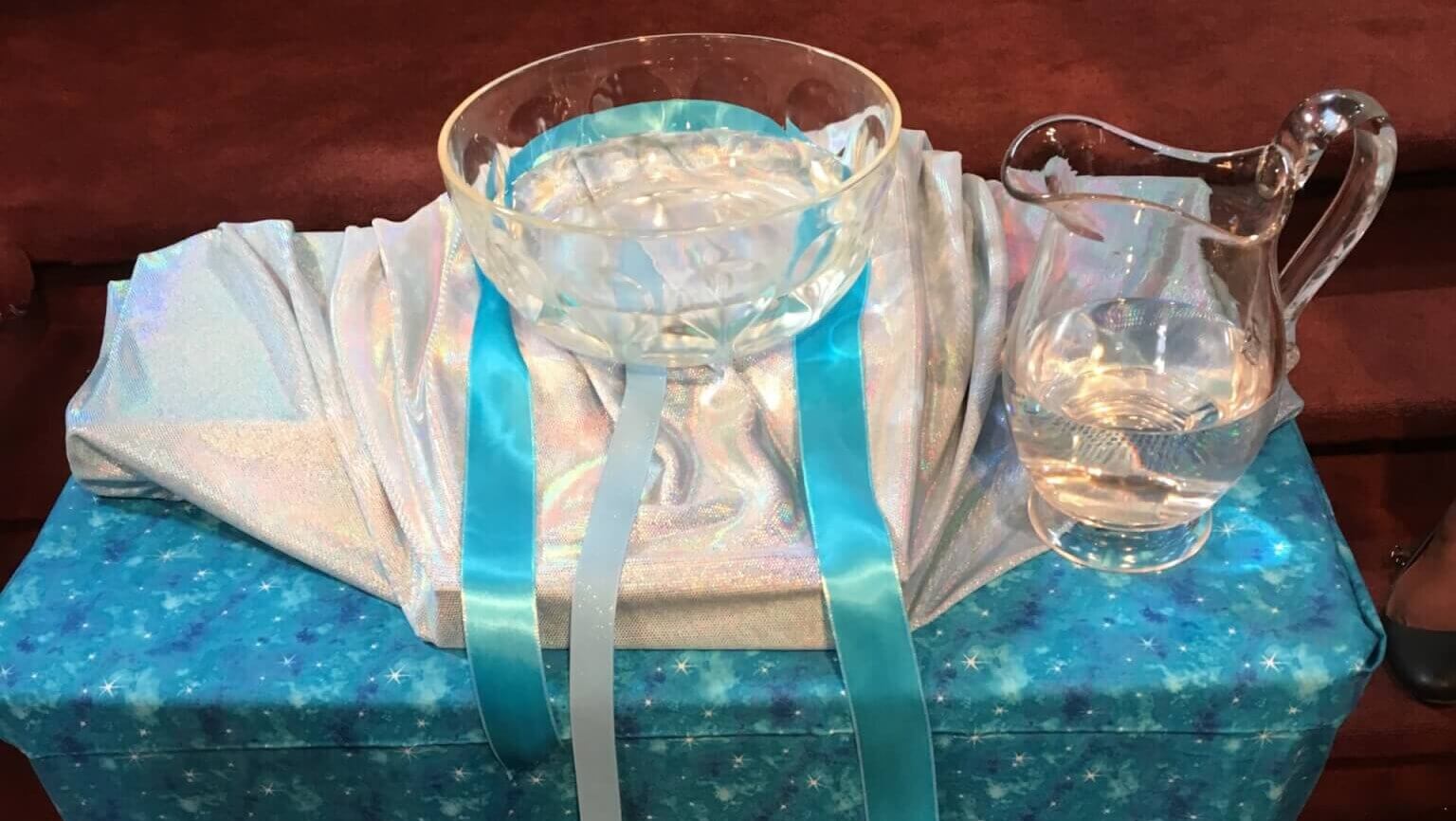 clear bowl of water and pitcher on a table with a pretty cloth
