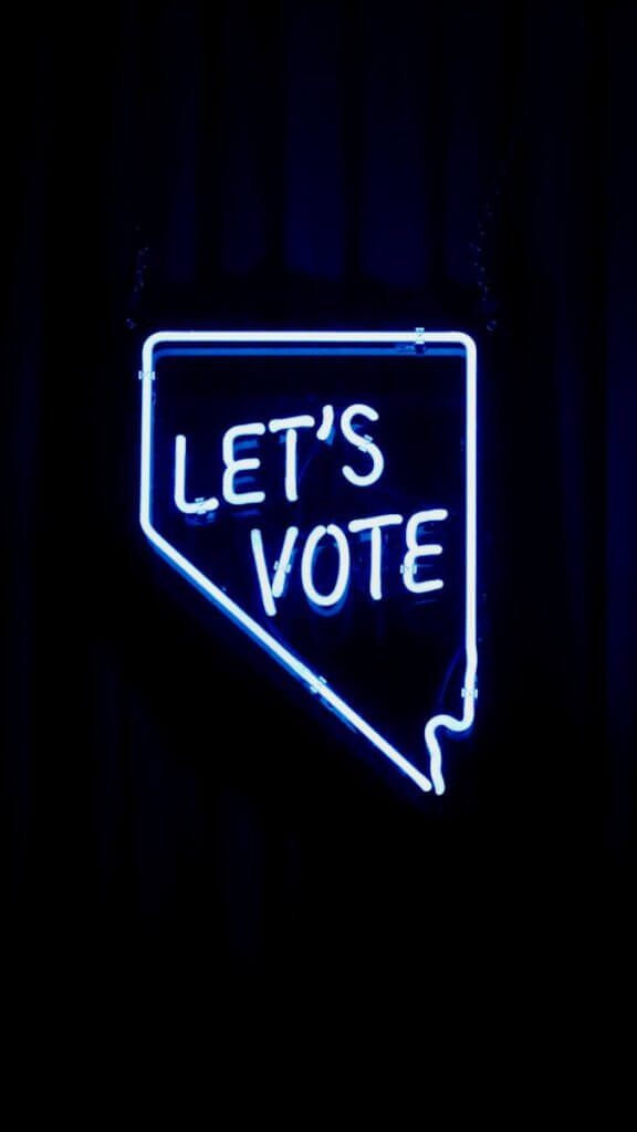 blue and white "Let's Vote" neon light signage; outline is shape of Nevada