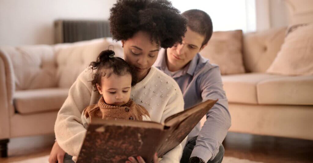 Mother, father, and child enjoying a storybook together in their cozy living room.