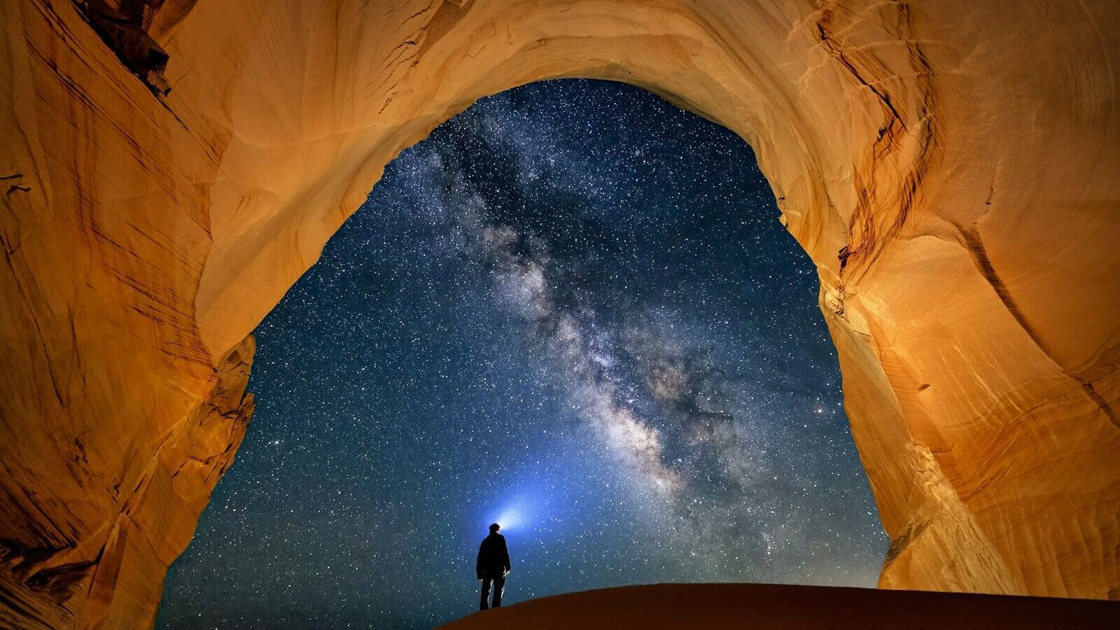a man standing in the middle of a desert under a star filled sky