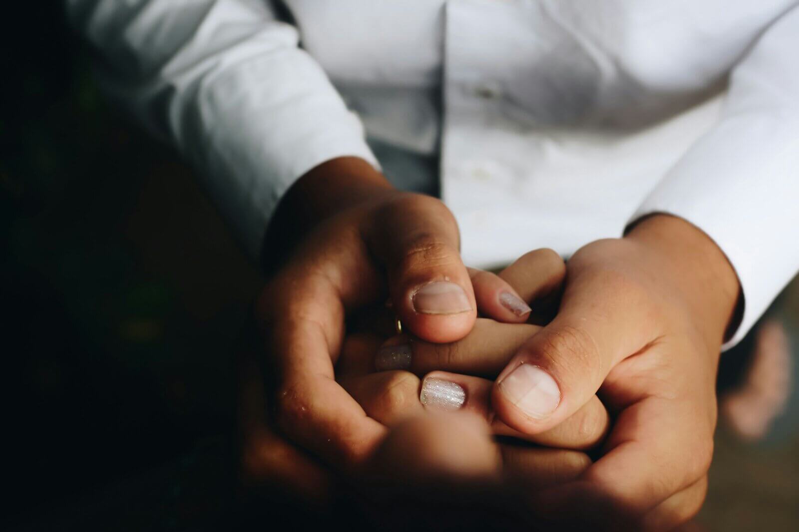 Two people holding hands, one wearing a white shirt